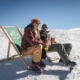 Sonniges Wetter und Schnee - Entspanntes Pärchen sitzt im Liegestuhl und trinkt ein Weissbier